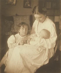 [Mãe de roupão, sentada, com bebé e filho pequeno].