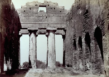 Interior do Templo da Concórdia, no Vale dos Templos, em Agrigento. Em primeiro plano, duas colunas dóricas; nas laterais, uma parede de perímetro arqueado.