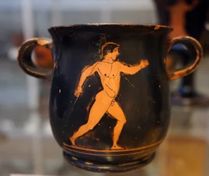 Caneca grega antiga vermelha sobre preto representando um atleta