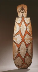 Escudo oval Asmat, entalhado em relevo com figuras estilizadas, máscara no topo (madeira)