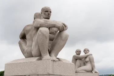 Esculturas de granito de dois homens nus sentados costas com costas; escultura de duas mulheres na parte de trás de uma escultura no Parque Frogner, Oslo, Noruega