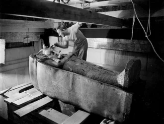 Descoberta do túmulo do faraó Tutankhamon no Vale dos Reis (Egito): na câmara funerária, Howard Carter trabalha na tampa do segundo caixão, outubro de 1925, fotografia de Harry Burton (p1568)