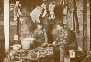 Meares e Demetri no fogão de gordura na Discovery Hut, 3 de novembro de 1911, 1913