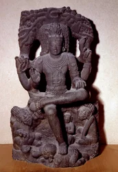 Hinduísmo: representação de uma das manifestações de Shiva sentada sobre uma pedra, com quatro braços, segurando um rosário, fogo, no gesto de ensinar e no de presente. Escultura do século XII-XIII Dim. 1,2 m; do Sul da Índia. Coleção C.T Loo