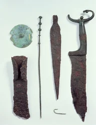 De cima para baixo: faca, ponta de lança, anzol, alfinete de roupa, disco de cinto e machado, todos encontrados em sepulturas masculinas em Hallstatt, Idade do Ferro