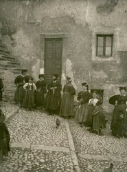 Mulheres e crianças vestindo roupas tradicionais nos degraus que levam à casa, Abruzzo, Itália