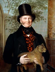 Retrato de Edward Cross, de meio corpo, com casaco preto e colete aos quadrados vermelhos, segurando uma cria de leão