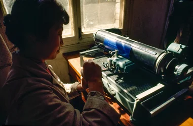 No escritório da comuna, um membro escreve numa máquina de escrever chinesa. Comuna de Chun Xing, Y...