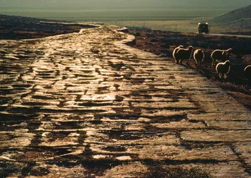 A estrada moderna de macadame é paralela à antiga estrada romana de calcário. Perto de Aleppo, Síria.