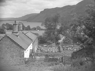 Edifícios agrícolas com ovelhas no pátio e Ullswater em fundo