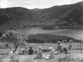 Grupo de pessoas sentadas na relva ou em espreguiçadeiras com vista para Thirlmere