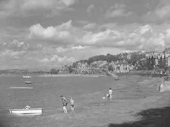 Pessoas a brincar em barcos com a água alta em Arnside, com o Albion Hotel em fundo