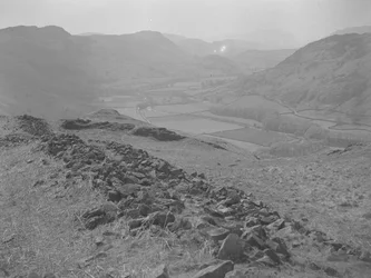 Vista de um vale aberto em Hardknott com pilhas de rochas em primeiro plano