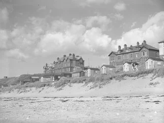 Vista da praia de Silloth de barracas de praia e casas ao longo do mar; paisagem marítima; frente