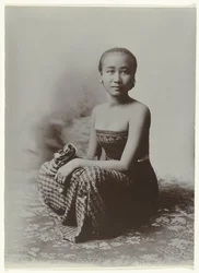 Retrato de estúdio de uma jovem javanesa sentada num sarongue com motivo batik