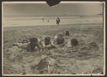 [Crianças a deitarem-se na areia da praia]
