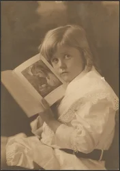 [Retrato de uma criança a segurar um livro aberto numa ilustração semelhante]