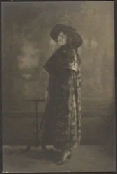 [Retrato de mulher de casaco comprido diante de uma tapeçaria]