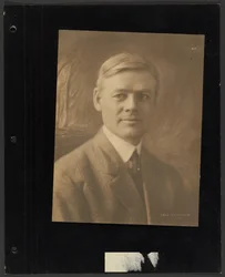 Retrato de um homem sentado diante de um cenário pintado