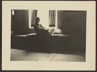 [Mulher sentada à janela].