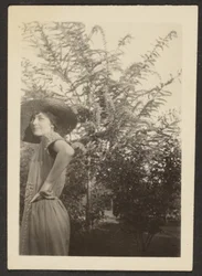 [Mulher de chapéu em pé no pomar].