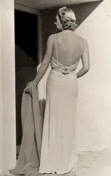 Modelo vista de trás usa vestido de noite da casa de alta costura "Fumach". O artigo deixa as costas nuas e é adornado com um alfinete com jóias. (foto a p/b)