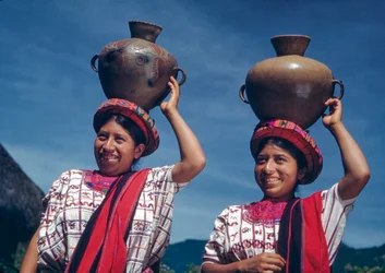 Mulheres guatemaltecas carregando jarros de água na aldeia de Nebaj, Guatemala