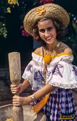 Mulher com chapéu de palha do Panamá a moer com um almofariz e um pilão tradicionais.