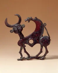 Antiguidades Orientais: placa de bronze na mandíbula que representa um monstro androcefálico atropelando uma corça. Do Luristão. 750 AC. Paris, Museu do Louvre.