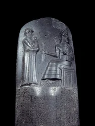 Mesopotâmia: estela de diorito do Código de Leis de Hammurabi. Está coberta de inscrições cuneiformes e, no topo, o rei Hammurabi está perante o deus solar mesopotâmico Shamash, divindade da Justiça. É uma das obras mais antigas.