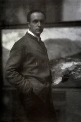 Retrato de três quartos de Cesare Maggi. O pintor, vestido de avental, está segurando uma paleta na mão esquerda. No fundo, a tela em que ele está trabalhando