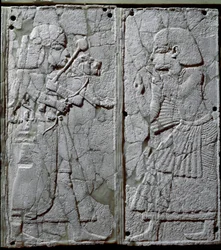 Civilização fenícia: ornamento de cama decorado com um baixo-relevo de marfim que representa um guarda a apresentar um leão ao rei. Proveniente do sítio de Ugarit, antiga cidade síria no tell de Ras Shamra. Século XIV a.C. Dimensões 24 cm. Damasco, Museu