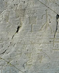 Pré-história, civilização dos Camunni, arte rupestre: uma rocha funerária com cenas de caça ao veado e da vida quotidiana numa aldeia. Período entre o Neolítico e a Idade do Bronze. Capo di Ponte, Parco nazionale delle incisioni rupestri di Naquane
