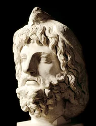 Arte romana: "cabeça barbuda coberta por um pássaro morto de Sarapis ou Serapis, deus grego-egípcio da morte" Escultura de mármore de Cartagoa. Século II. Escultura em mármore de Cartagoa. 60 cm Paris, Musee du Louvre