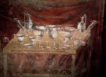 Vista de uma mesa coberta com pratos de prata (fresco