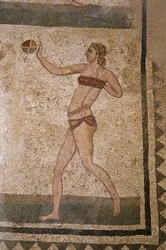 Mulher a jogar à bola. Jovens romanos envolvidos em exercícios físicos. Eles usam uma tanga ao redor dos rins e um estrofio (ancetra do sutiã) no peito. Uma tanga à volta dos rins. Mosaico romano do século III - IV de Villa del Casale, Piazza Armerin.