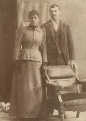 Fotografia de um casal afro-americano em pé atrás de uma cadeira, ca. 1890.
