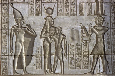 Antigo Egito, Pintura mural/escultura, Ísis amamenta o jovem faraó na presença da criança divina Ihy, enquanto o faraó faz uma oferenda, Templo de Hathor, Dendera (foto)