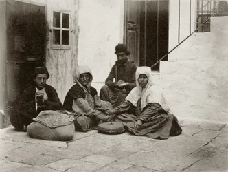 Mulheres moendo farinha com moinhos redondos dentro de um pátio de uma casa em Jerusalém, 1867