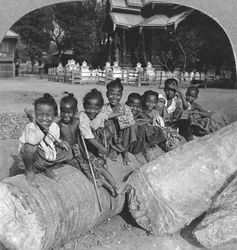 Birmanês crianças sentadas em um tronco de palmeira, Birmânia, 1908