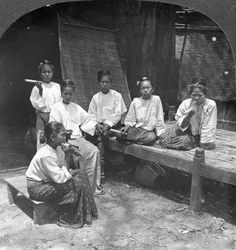 Mulheres birmanesas que fumam fora de sua casa, Mandalay, Birmânia, 1908.