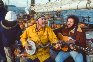 O músico e ambientalista Peter Seeger toca banjo no convés do Clearwater no...