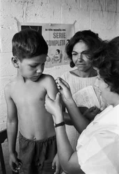 Uma enfermeira vacina um rapaz equatoriano numa missão do navio-hospital SS Hope