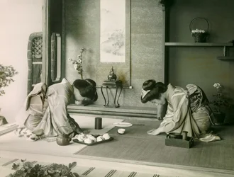 Duas mulheres japonesas em trajes tradicionais cumprimentam-se antes da cerimónia do chá, cerca de 1900 - 1915 (fotografia)