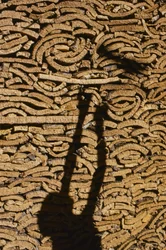 Sombra de um homem a empilhar cortiça para exportação de Marrocos