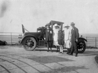 Um grupo de pessoas na frente de seu carro à beira-mar, c1920s