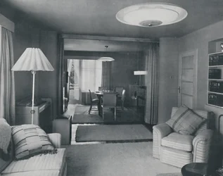 Sala de jantar e sala de estar, divididas apenas por cortinas pesadas em um atraente tecido moderno, 1942