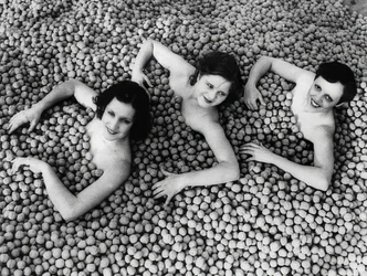 Três jovens mulheres tomam banho em um mar de nozes. America. 1932