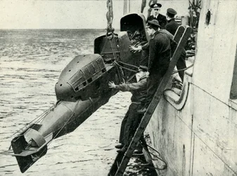 Levantar um torpedo equipado com carruagem a bordo de um navio, Segunda Guerra Mundial, 1945.