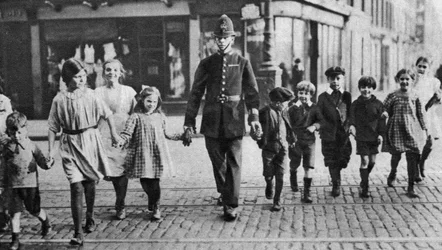 Policial ajudando crianças em idade escolar do outro lado da estrada, East End, Londres, 1926-1927